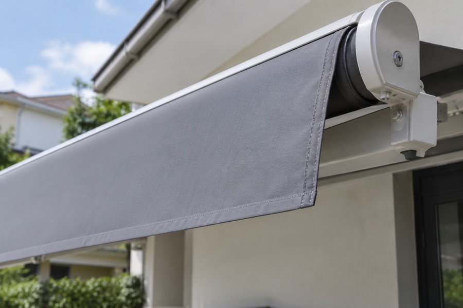 Close-up of the fabric roller edge and neatly attached replacement cover on an awning frame, believable mechanical connection
