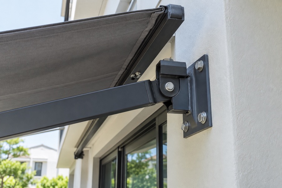 Close-up of awning wall bracket and fixing bolts on painted concrete, clear inspection view without workers