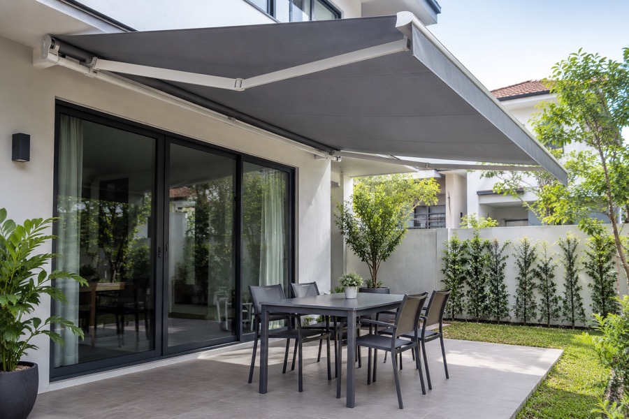 Well-aligned grey retractable awning operating over an empty modest patio, clean fitted fabric, illustrative restored condition not a before-after collage