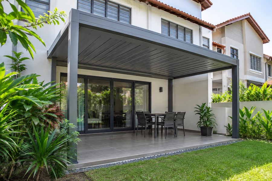 Small backyard patio with a closed aluminium louvre roof viewed from outside, ordinary terrace house and tropical planting