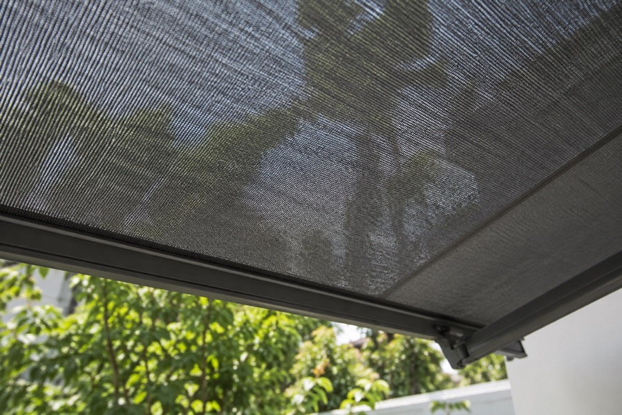 Close-up of textured dark grey outdoor sunscreen fabric with diffuse garden light filtering through, a clear product material photograph